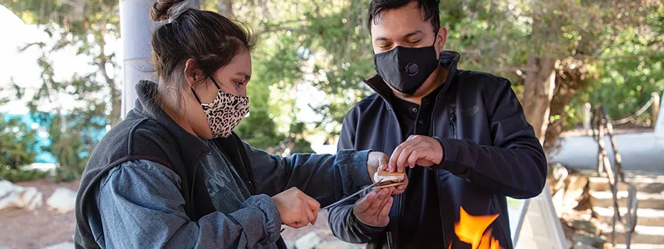 Two people making Smores over a fire