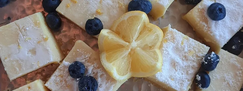 spread of lemon bars with a carved lemon and blueberries