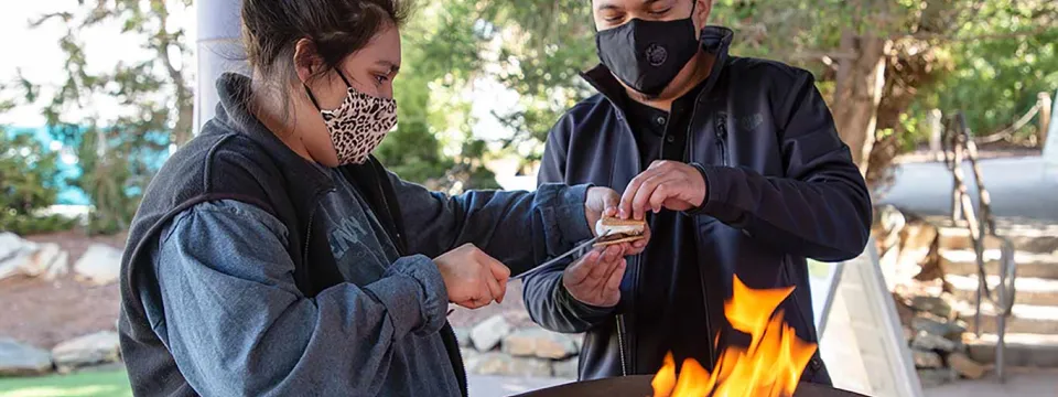 Two people making Smores over a fire