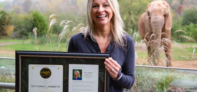 Toy Lambeth holding award in front of an elephant