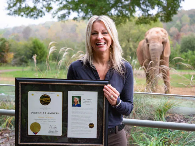 Toy Lambeth holding award in front of an elephant